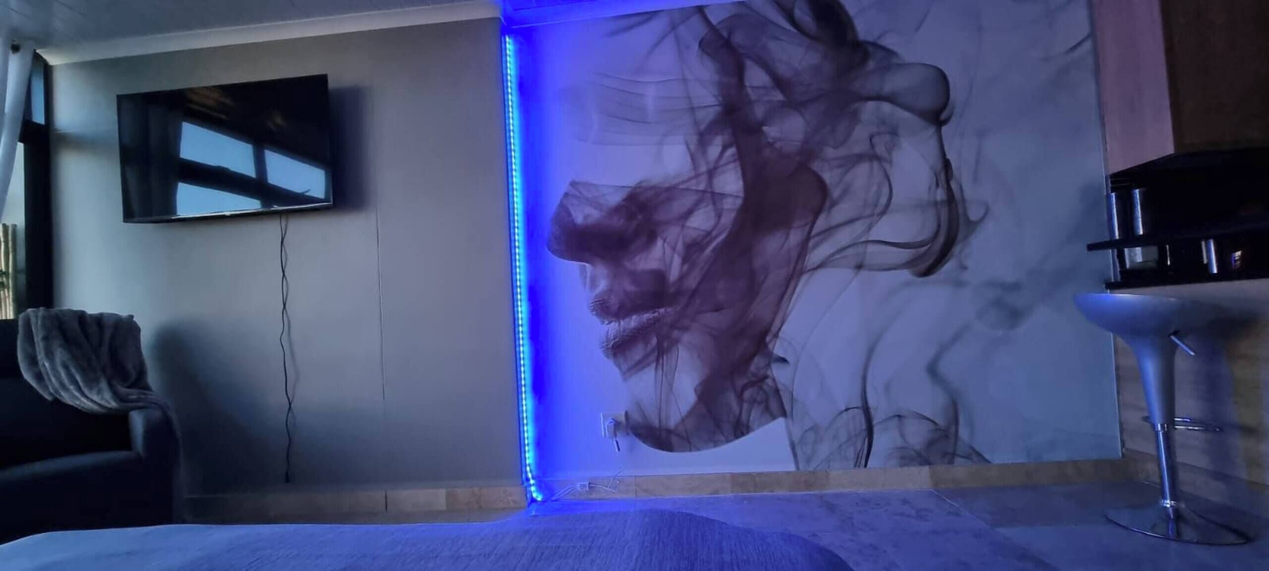 Une chambre moderne dotée d’un grand tableau abstrait, d’un téléviseur à écran plat et d’un coin bar.