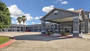 Un motel con zona de estacionamiento techada, una vía contra incendios y un edificio con varios balcones.