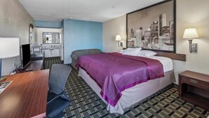 Habitación de hotel con cama, escritorio, silla, televisión y un cuadro con una vista urbana.