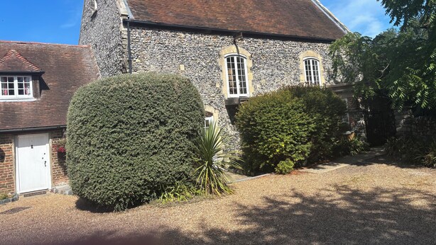 A stone building with a tiled roof, a white door, and a gravel driveway. - Manston Court Accommodations.  3 attached properties.  Sleeps up to 22 guests (Ramsgate)