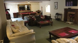 A traditional living room with a pool table, leather sofas, and a fireplace. - Manston Court Accommodations.  3 attached properties.  Sleeps up to 22 guests (Ramsgate)
