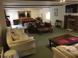 A traditional living room with a pool table, leather sofas, and a fireplace. - Manston Court Accommodations.  3 attached properties.  Sleeps up to 22 guests (Ramsgate)