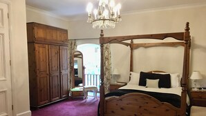 A four-poster bed with a wooden frame, a chandelier, a wooden wardrobe, and a mirror. - Manston Court Accommodations.  3 attached properties.  Sleeps up to 22 guests (Ramsgate)