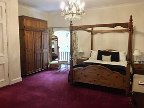 A four-poster bed with a wooden frame, a chandelier, a wooden wardrobe, and a mirror. - Manston Court Accommodations.  3 attached properties.  Sleeps up to 22 guests (Ramsgate)