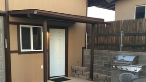 Une terrasse avec un barbecue, une porte et une petite table.