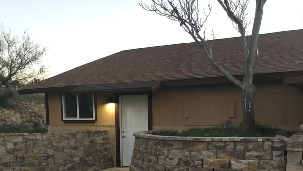 Une maison d’habitation avec un mur en pierre, une allée pavée et une porte.