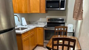 Une cuisine avec des meubles en bois, un réfrigérateur en acier inoxydable, un four à micro-ondes, un four traditionnel et une table à manger avec des chaises.