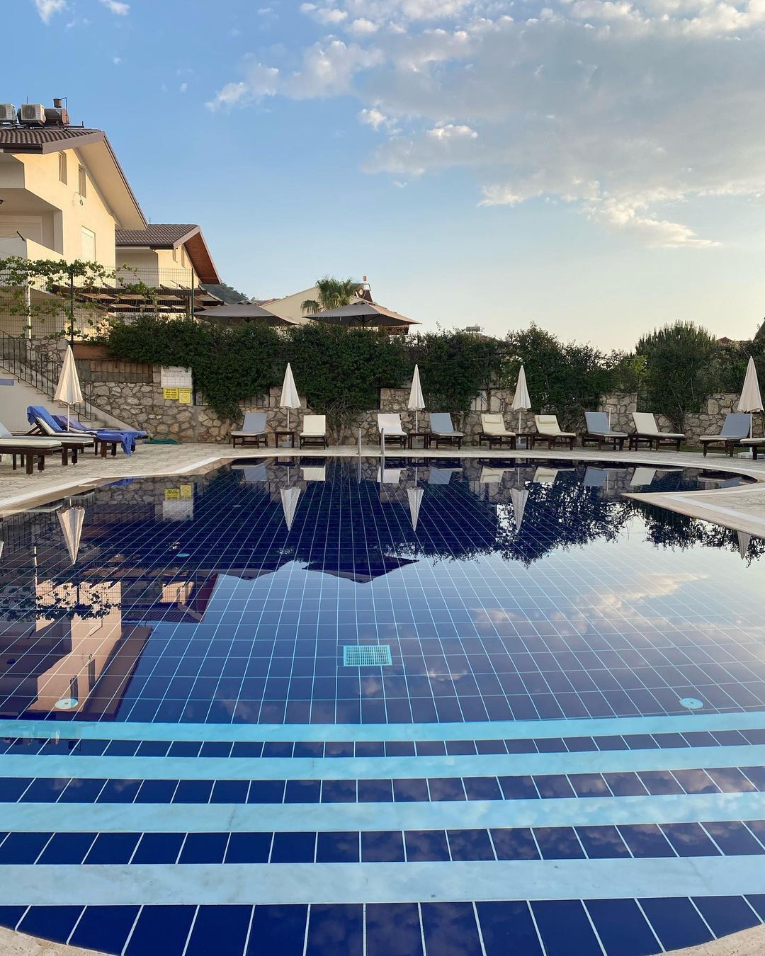 Una piscina al aire libre de temporada, sombrillas, tumbonas