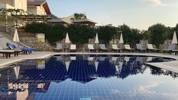 Une piscine dotée d’un toit en panneaux solaires, de chaises longues et d’un mur en pierre.