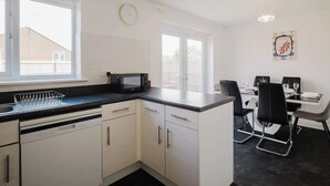 Une cuisine moderne avec des meubles blancs, un plan de travail noir et un coin repas comprenant une table et des chaises.