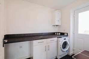 A laundry room with a washing machine, a cabinet, and a countertop. - Spacious 4 Bedroom House With Free Parking (West Midlands)