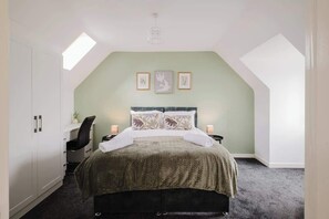 A bedroom with a bed, bedside lamps, a desk, and a chair. - Spacious 4 Bedroom House With Free Parking (West Midlands)