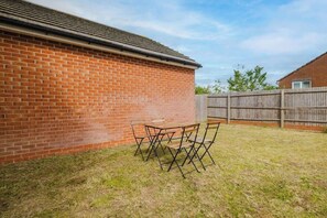 A brick building with a wooden fence and a grassy yard. - Spacious 4 Bedroom House With Free Parking (West Midlands)