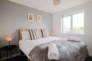 A bedroom with a bed, a bedside lamp, a window, and two framed pictures on the wall. - Spacious 4 Bedroom House With Free Parking (West Midlands)