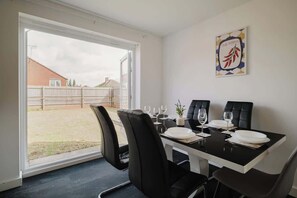 A dining area with a table set for four, chairs, and a view of the outside. - Spacious 4 Bedroom House With Free Parking (West Midlands)