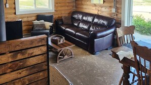 Ein Blockhaus-Interieur mit Ledersofa, Holzesstisch und einer Kronleuchter.