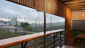 A balcony with a wooden railing, a view of a fenced area, and a building in the background. - Villas en Guatape  (Guatape)