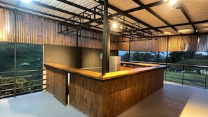 A modern interior with a wooden reception desk, metal beams, and large windows offering a view of a green landscape. - Villas en Guatape  (Guatape)