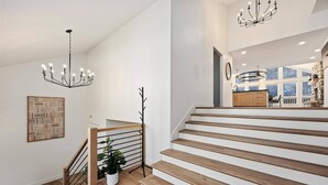 En modern trappa med trästeg och metallräcken, en kristallkrona och en krukväxt.