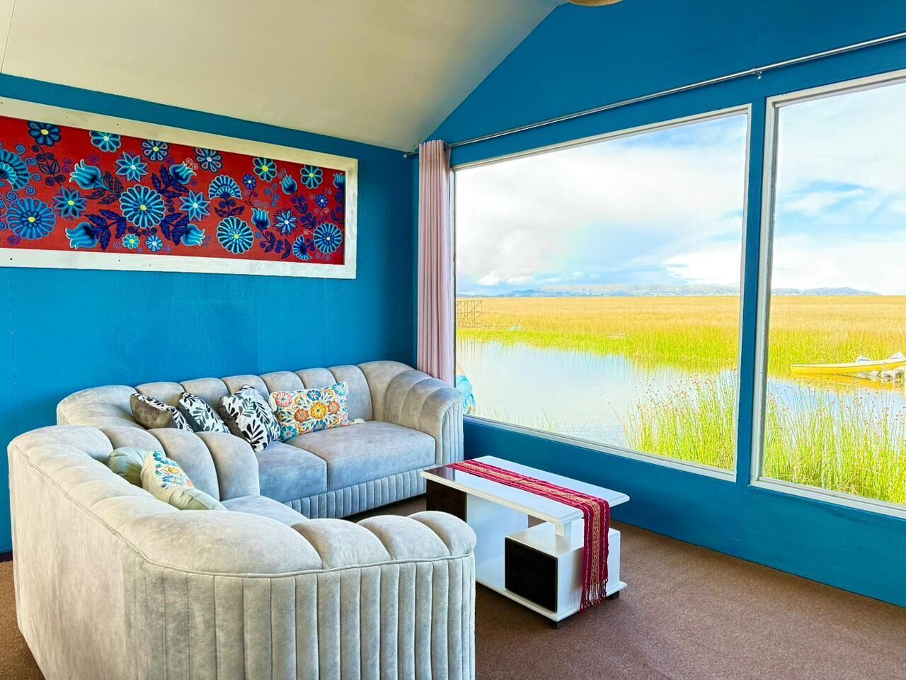 A room with a large window, a sofa, and a small table.