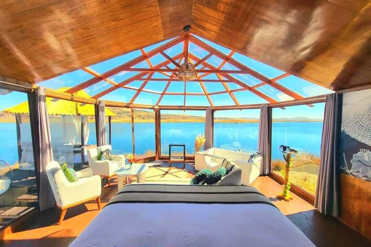 A bedroom with a large bed, a glass ceiling, and a view of the sea.