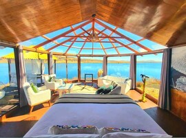 Un dormitorio con una cama grande, techo de cristal y vista al mar.