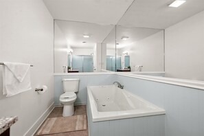 Ein modernes Badezimmer mit Toilette, Badewanne und einem großen Spiegel.