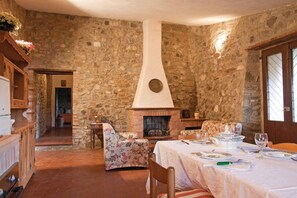 Ein Zimmer mit Steinsandsteinwänden, einem Kamin, floralen Möbeln und einem Esstisch für vier Personen.