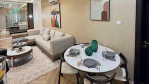 Una sala de estar moderna con comedor, un sofá, una mesa de centro y una mesa de comedor con platos y vasos.