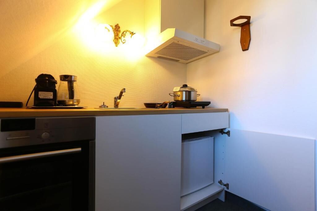 A compact kitchen with a coffee maker, a pot on the stove, and a wall-mounted knife.