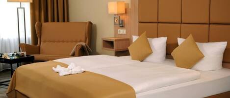 A hotel room with a large bed, a chair, a nightstand, and a lamp.