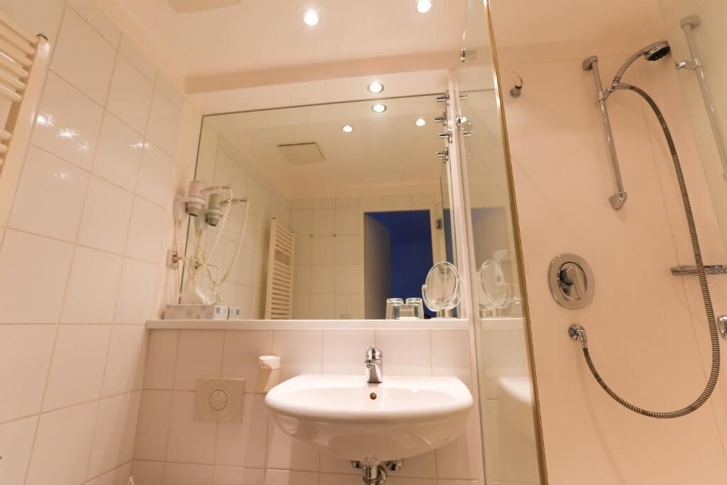 A bathroom with a glass-enclosed shower, a white sink, and a mirror.