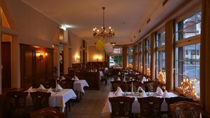 Ein Restaurant mit mehreren Tischen, Stühlen und einer imposanten Leuchter.
