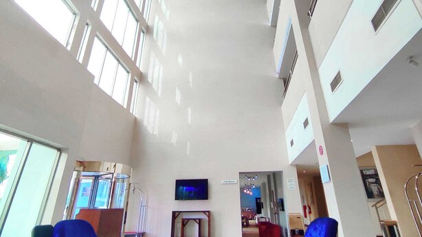 A spacious lobby with high ceilings, large windows, and modern furniture.