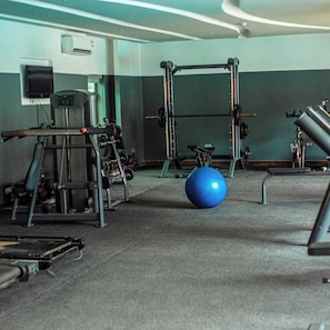 A gym with weightlifting equipment, a blue exercise ball, and a television on the wall. - The Addrex Hotel And Suites (Aba)