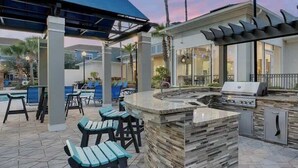 Ein Außenbereich mit Küche, Grill, Bar und Pool.