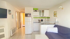 Een knus woongedeelte met een kitchenette, een eethoek en een bank.