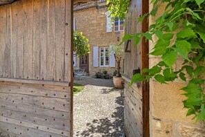 A narrow cobblestone alley with a wooden door and a stone building in the background. - Holiday Home “La Maison de Marie” with Shared Terrace, Wi-Fi & Air Conditioning (Domme)