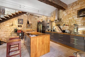 A kitchen with a wooden island, stone walls, and a built-in stove. - Holiday Home “La Maison de Marie” with Shared Terrace, Wi-Fi & Air Conditioning (Domme)