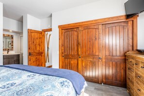 A bedroom with a large bed, wooden wardrobe, and a television on a dresser. - Mountain View Snowcreek Condo with Community Hot Tub and Fireplace (Mammoth Lakes)
