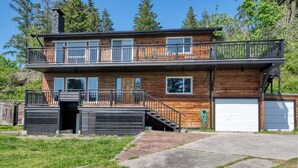 A two-story wooden house with a balcony, a garage, and a driveway.
