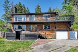 Une maison en bois à deux étages, dotée d’un balcon, d’un garage et d’une allée.