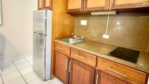 Eine Küche mit Holzausstattung, einem Edelstahlkühlschrank, einer Granit Arbeitsplatte und einem Schneidebrett.