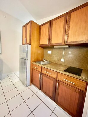 A kitchen with wooden cabinets, a stainless steel refrigerator, a granite countertop, and a black cutting board. - Villa 12 Flamenco Beachfront Villas (Flamenco)