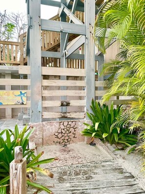 A wooden gate leading to a building with a stone wall and tropical plants. - Villa 12 Flamenco Beachfront Villas (Flamenco)