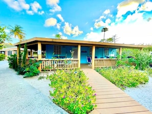A beachfront building with a covered patio, a wooden deck, and lush greenery. - Villa 12 Flamenco Beachfront Villas (Flamenco)