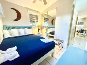 A hotel room with a bed, a desk, a chair, and a mirror. - Villa 12 Flamenco Beachfront Villas (Flamenco)