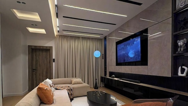 Uma sala de estar moderna com um sofá, mesa de centro e TV fixada na parede.