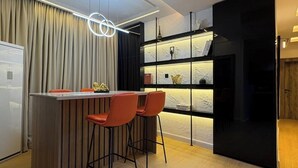 Uma cozinha moderna com bancada, piso de madeira e iluminação pendente.