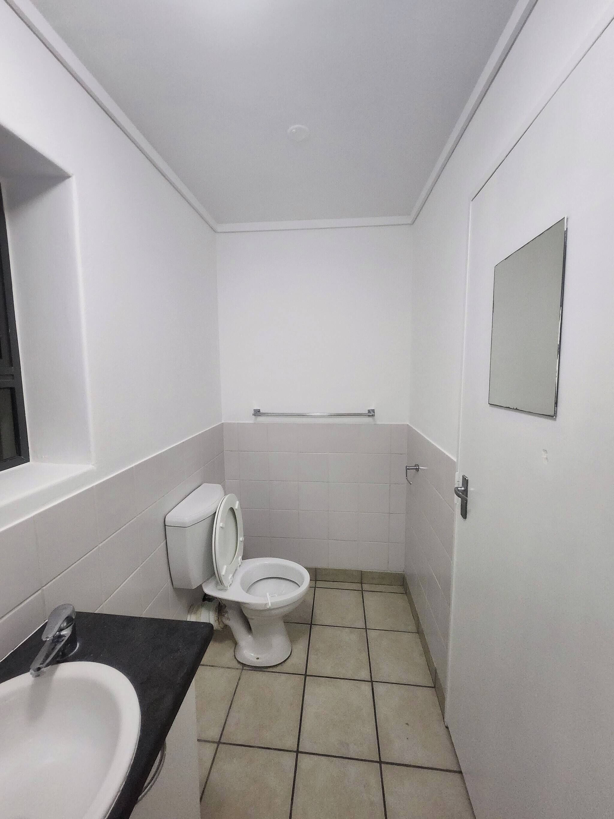 A small, clean bathroom with a toilet, sink, and mirror.